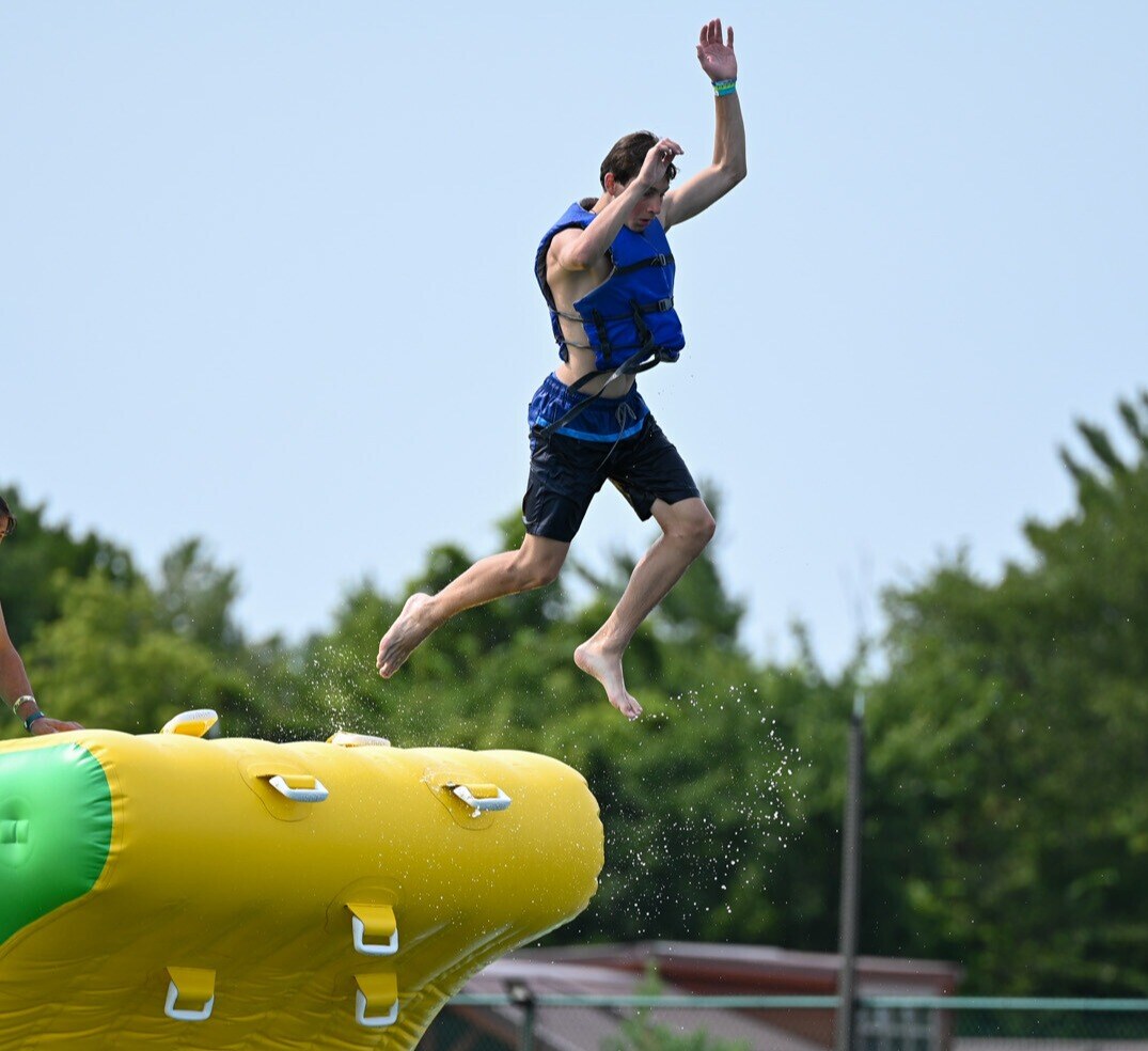 A Jellystone camper jumping off of an inflatable cliff at Adventure Island.