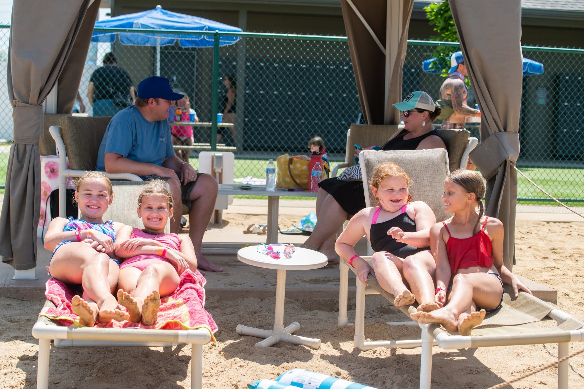 Four young girls relaxing on beach chairs near their cabana at Bear Paw beach on a warm sunny day.