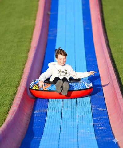 Young boy sliding down Randy's Thrill Hill, the super mega slide at Bear Paw Adventure Park, during the summer.