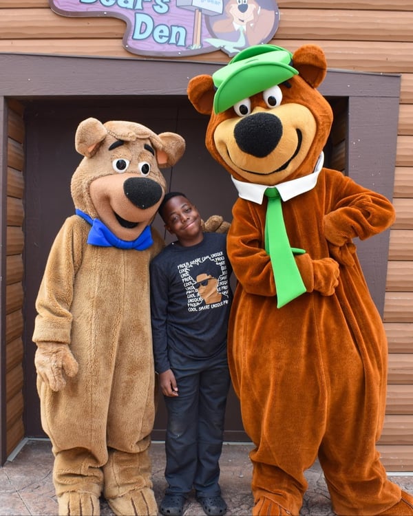 An image of a boy posing with Yogi Bear™ and Boo Boo™ at Jellystone Park™ Caledonia.