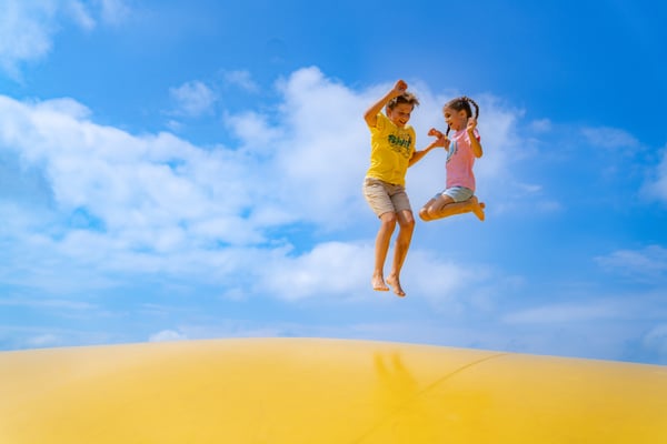 Two kids jumping on a jumping pillow on a warm sunny day in the middle of summer at Jellystone Park™ Caledonia. Two kids jumping on a jumping pillow on a warm sunny day in the middle of summer at Jellystone Park™ Caledonia.