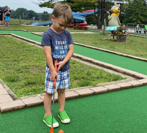 An image of a boy playing mini golf at Jellystone Park™ Caledonia.