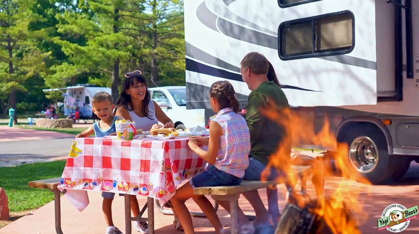 An image showing a family relaxing at their camper on vacation at Jellystone Park.
