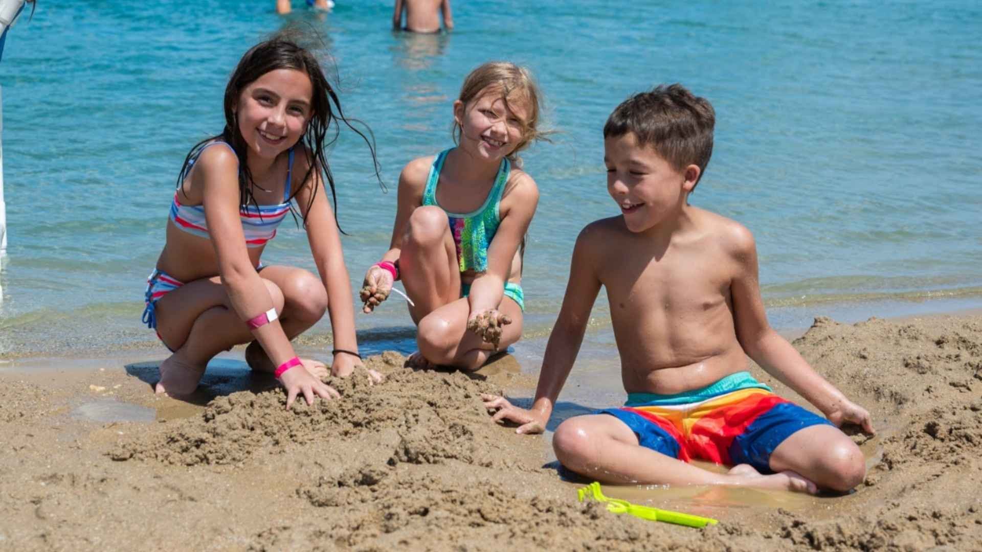 An image of 3 Jellystone campers having fun in the sand at Bear Paw Beach.