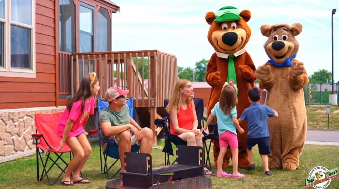 An image of a family camping at Jellystone Park having fun with the mascots.