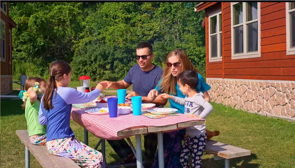 An image from Jellystone Park - Caledonia featuring a family sitting down to eat breakfast in the morning.