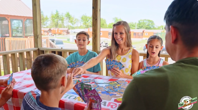 An image of a family at Jellystone Park playing cards in their cabin.