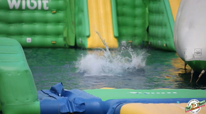 An image of a Jellystone camper having jumped off of the Wibit into the water at Bear Paw Beach.