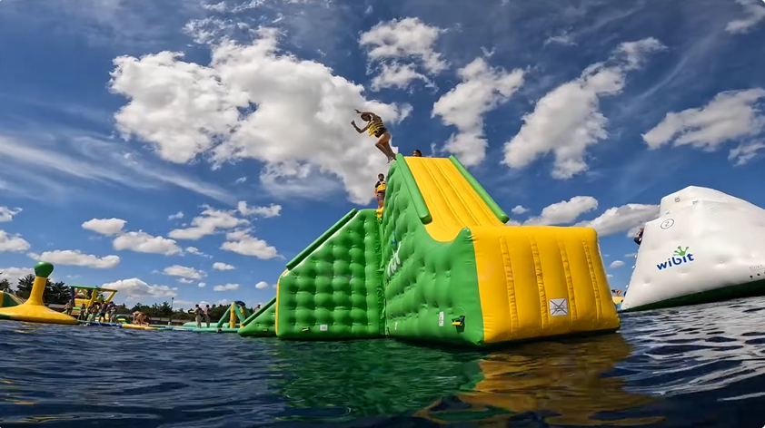 An image from Jellystone Caledonia showing a Chicago camper jumping off of the Wibit into the water.