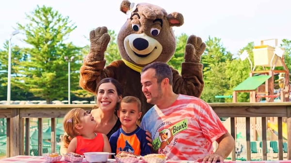 An image of a family posing with Cindy Bear™ at Jellystone Park™ Caledonia.