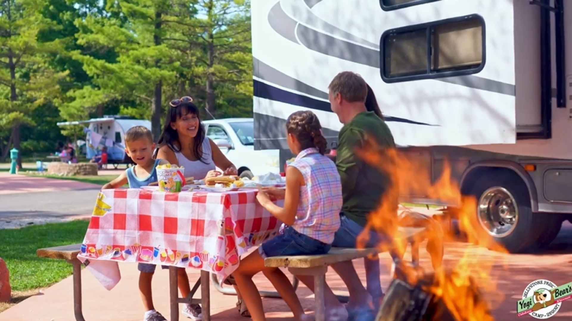 An image of a family at Jellystone Park with their RV and kids.