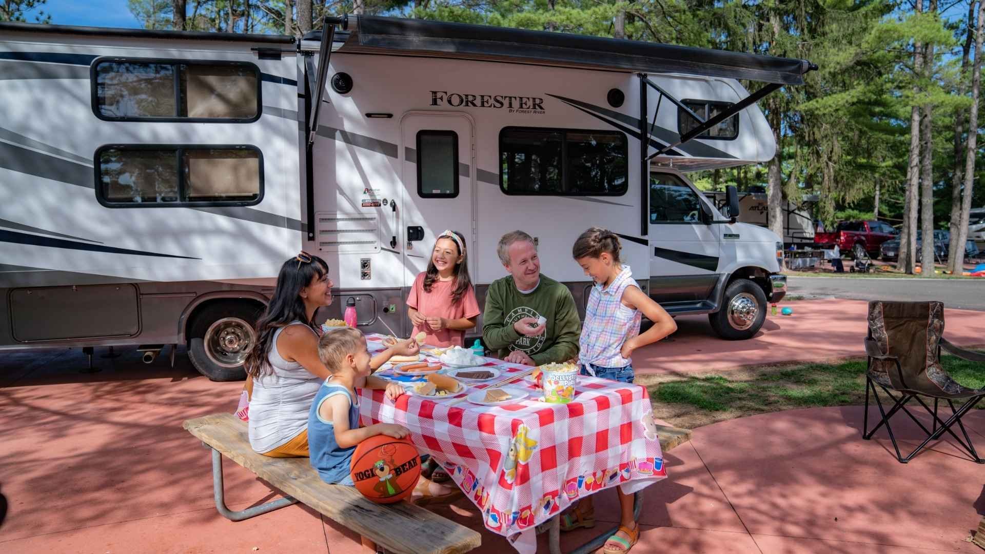 An image of a family camping at Jellystone Park outside of their RV.