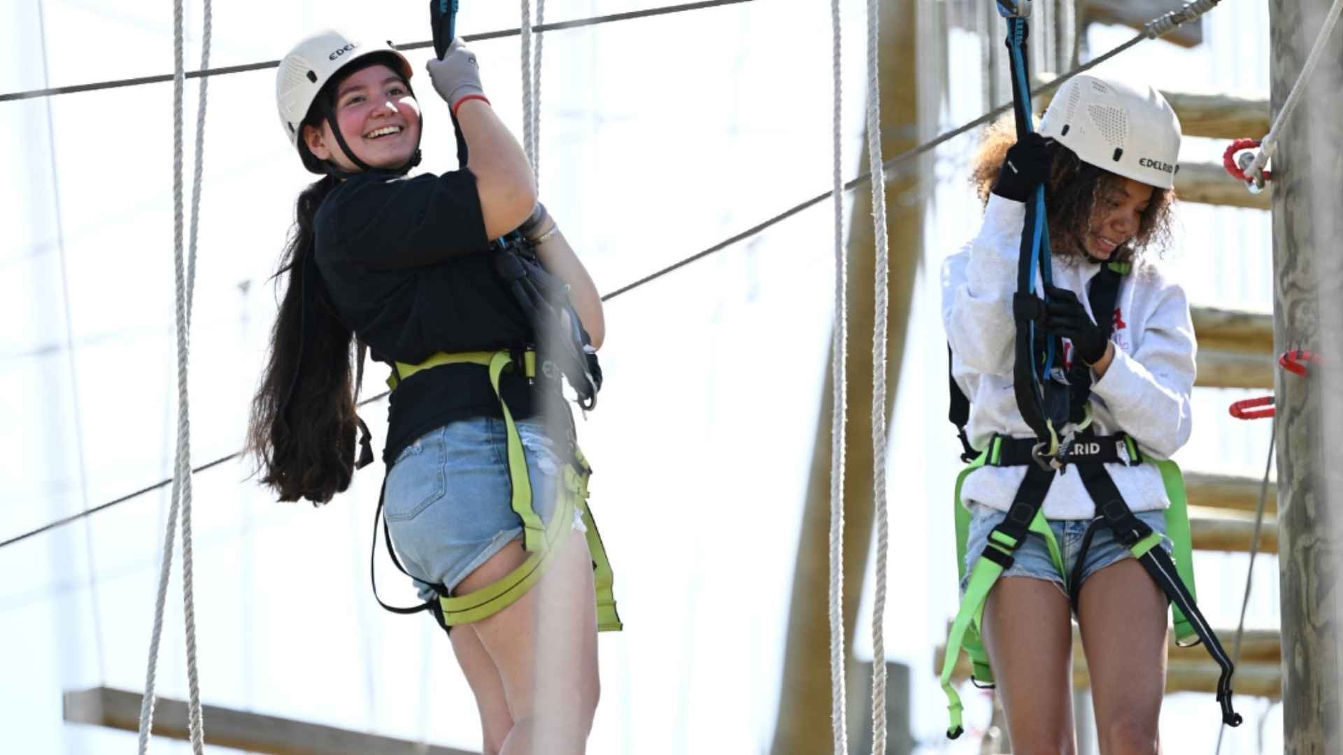 Two Jellystone campers having fun on the ropes course at Bear Paw Adventure Park.