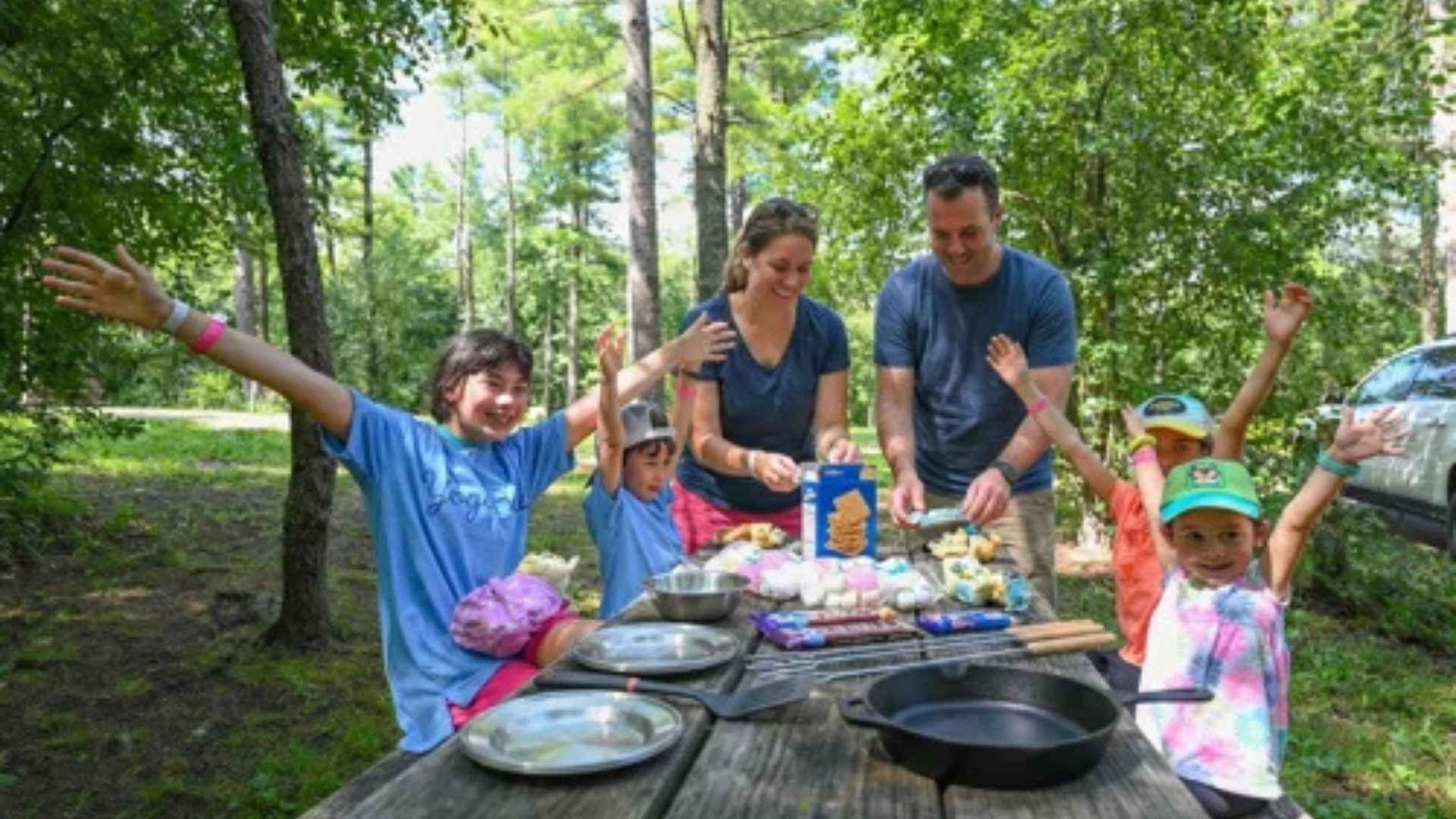 An image of a family at Jellystone Park having fun and making s'mores.