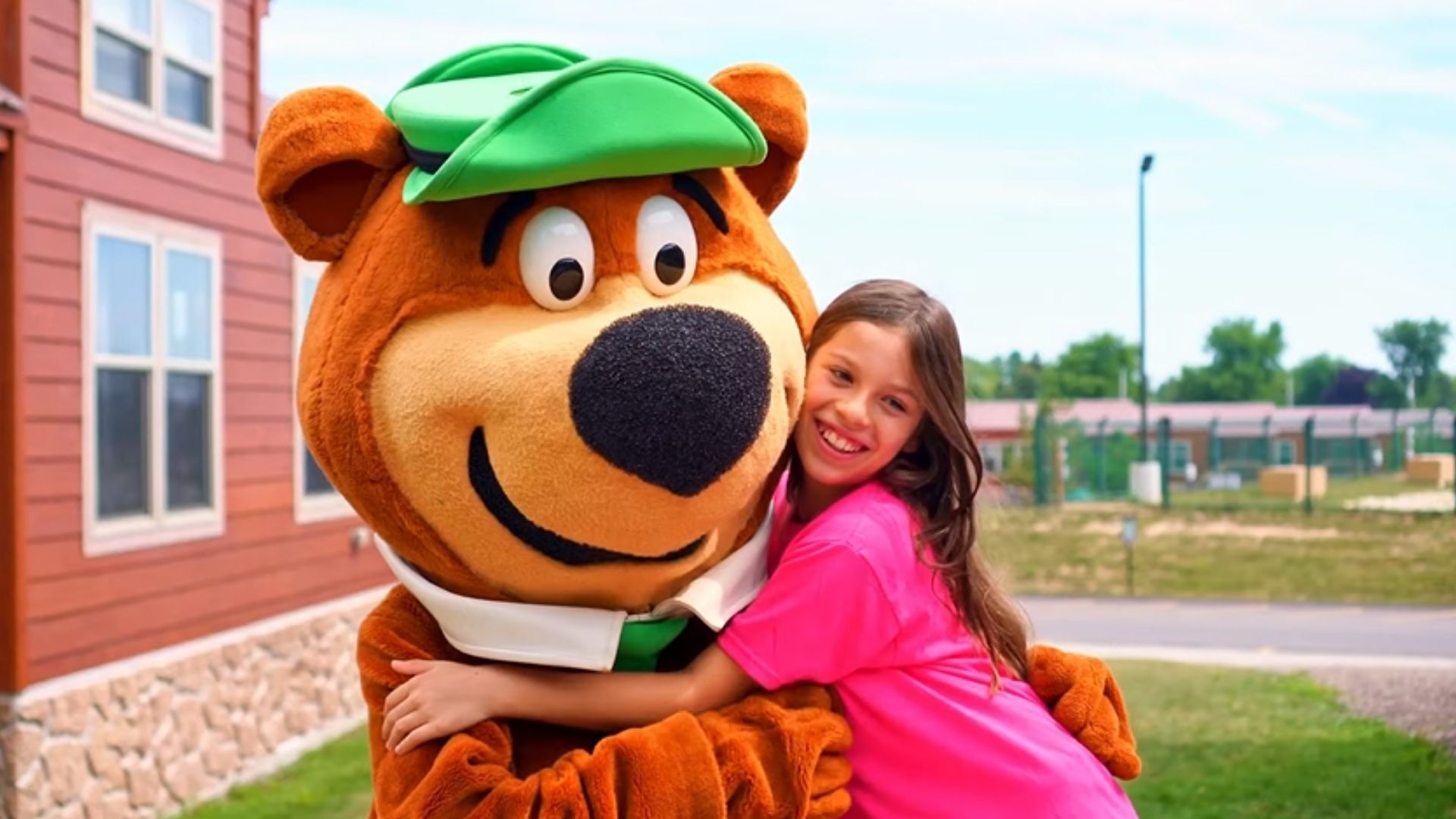 An image of a girl hugging Yogi Bear™ outside a cabin at Jellystone Park™ Caledonia.